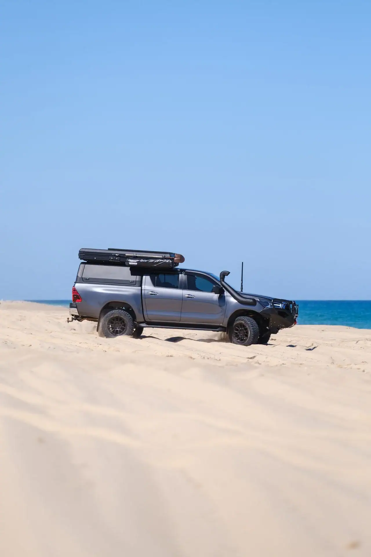 Hilux with canopy and rooftop tent on a coastal dune, side on