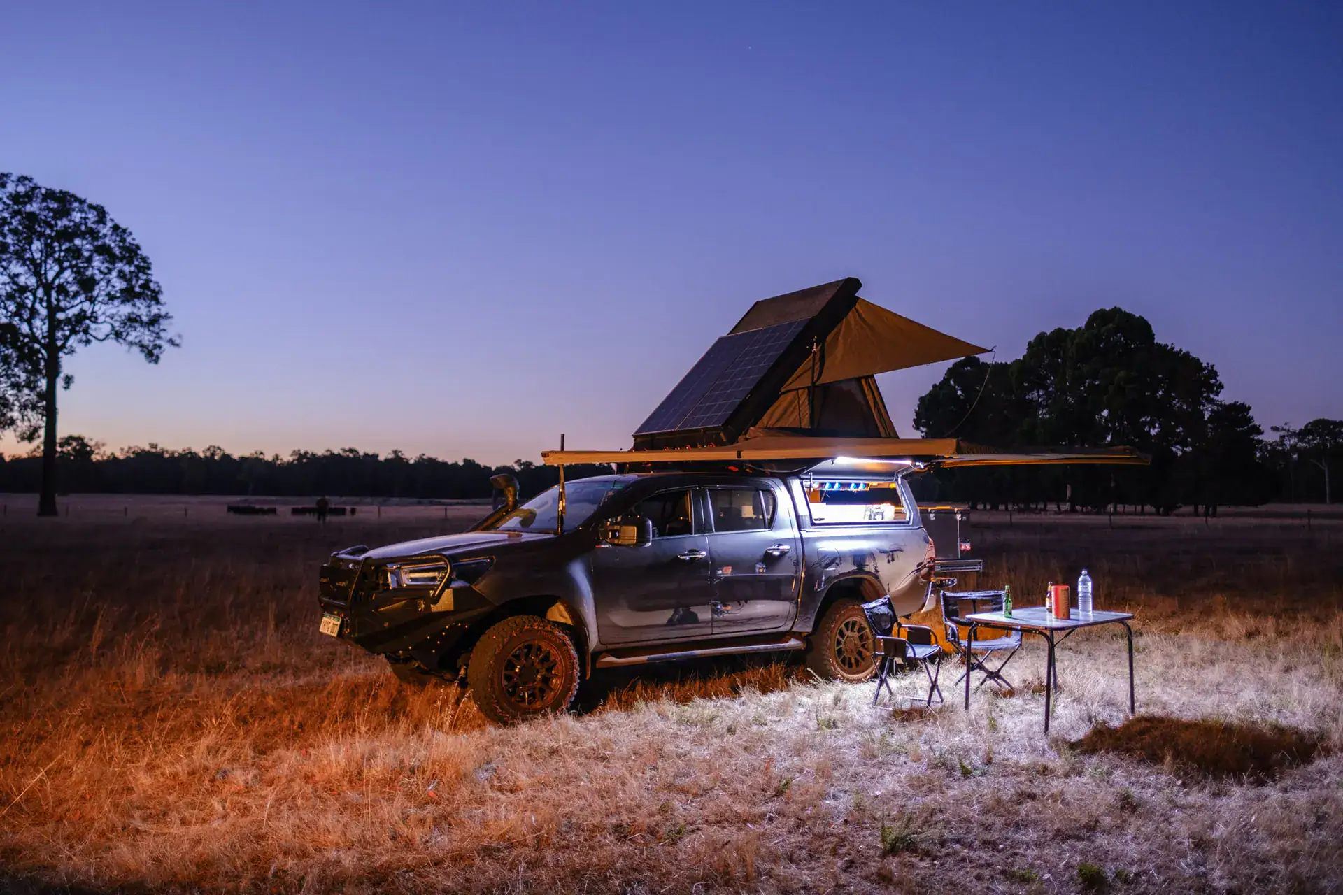 Fully loaded touring 4WD at dusk camp with rooftop tent, solar and awning set up