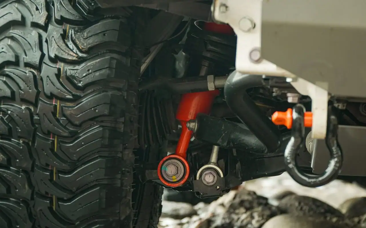 Outback Armour suspension fitted under a 4WD, orange control arm and shock detail