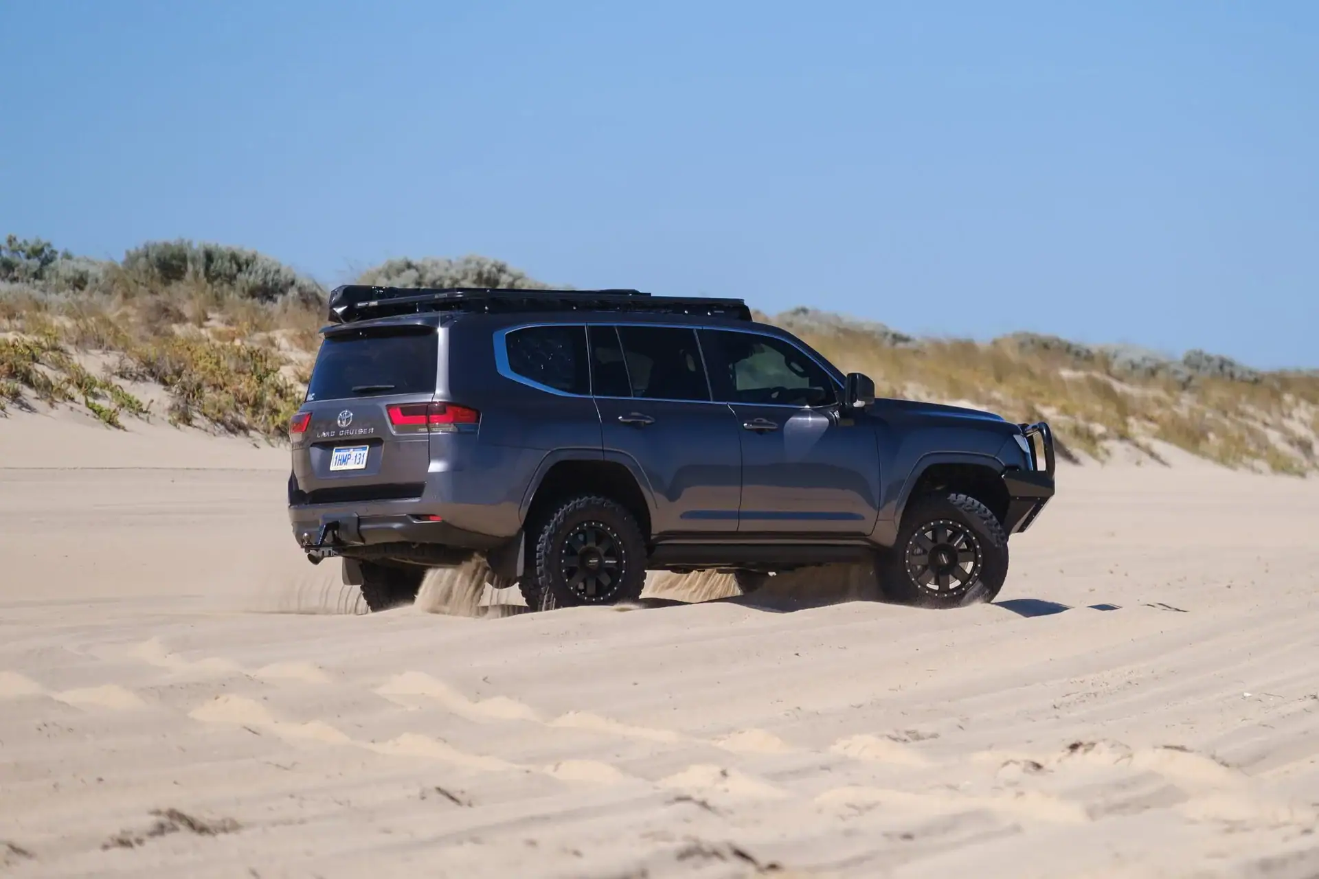 LandCruiser 300 Series climbing a sand dune, rear three-quarter view